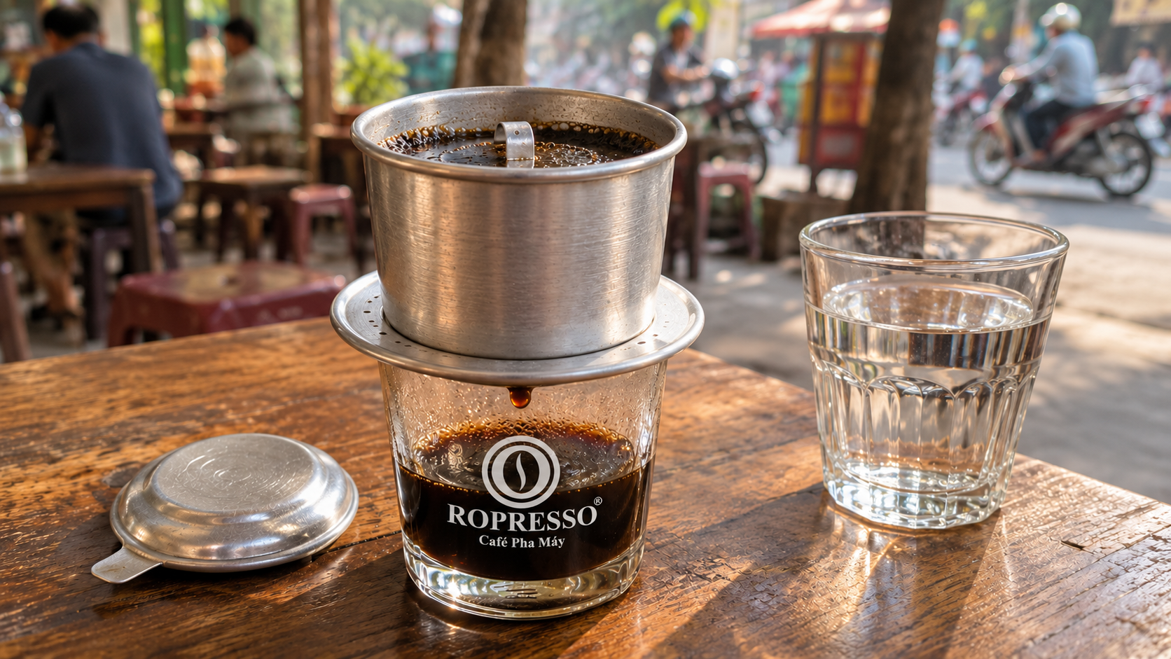 Phin nhôm không quai đặt trên ly cà phê đen có logo Ropresso tại bàn quán.
