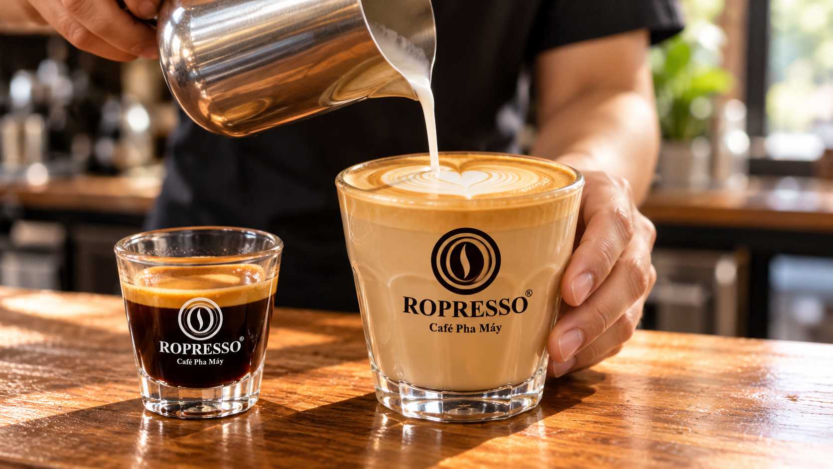 Rót sữa tạo latte art vào ly latte cạnh ly espresso nhỏ, hai ly có logo ROPRESSO.